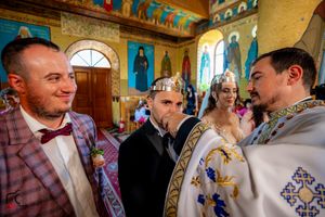 Wedding ceremony participants gathered inside a Byzantine-style church with decorated walls and arches.