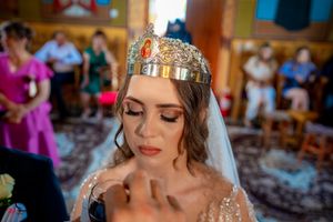 Close-up shot of a bride wearing a delicate crystal crown in an Orthodox church setting.