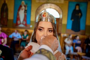 Orthodox wedding ceremony in progress with ornate golden icons and blue walls in the background.