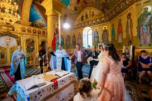 Interior view of an Orthodox church wedding ceremony with golden iconography and ornate decorations.