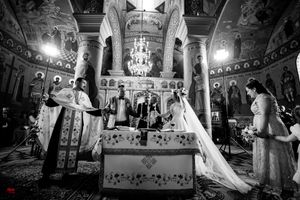 Black and white photo of a traditional Orthodox church wedding ceremony with ornate decorations and chandeliers.