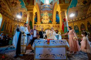 Orthodox wedding ceremony in a church with vibrant turquoise walls and golden ornate columns.