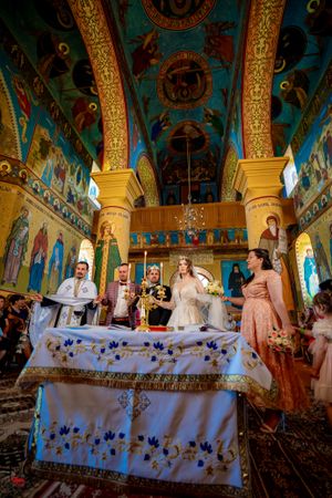 Religious ceremony in progress at an Orthodox church with beautifully painted walls and decorative altar table.