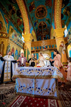 Wedding celebration inside a Byzantine-style church featuring elaborate wall paintings and ceremonial table.