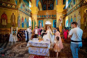 Wedding guests gathered in a Byzantine church with colorful frescoes and ceremonial decorations.