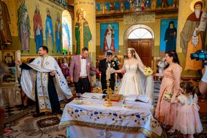 Traditional ceremony in progress within an ornately decorated Orthodox church with painted murals.