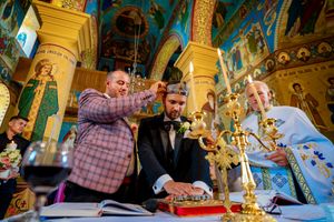 Orthodox church ceremony with golden columns and traditional religious iconography on turquoise walls.