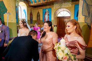 Wedding party gathered in an Orthodox church with colorful frescoes and golden decorations.