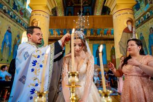 Wedding ceremony participants standing before ornate religious icons in a Byzantine church.