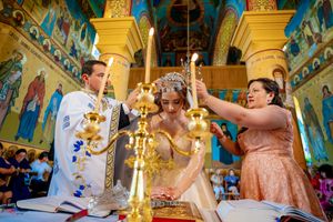 Traditional Orthodox wedding service with ceremonial candles and decorated altar area.