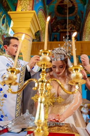Wedding ceremony participants performing traditional Orthodox rituals with crowns and candles.