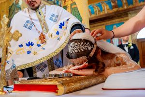 Close-up of hands during Orthodox wedding ceremony with religious texts and ceremonial items.