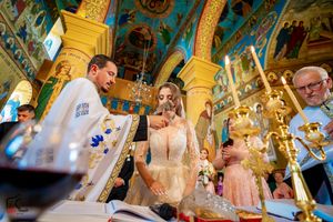 Wedding celebration inside historic Orthodox church featuring vibrant murals and gilded decorations.