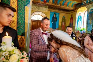 Ornate Orthodox church interior with colorful frescoes serves as backdrop for wedding ceremony.