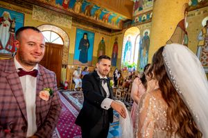 Wedding service taking place beneath ornate golden chandeliers in Byzantine-style church interior.