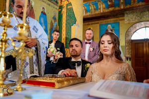 Religious ceremony underway in beautifully decorated Orthodox church with traditional iconography.