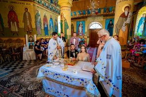 Solemn wedding ceremony conducted in historic Orthodox church with traditional religious iconography.