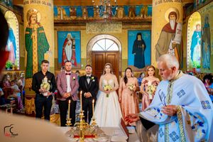 Orthodox wedding ritual performed in church with stunning frescoes and traditional religious artwork.