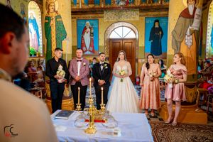 Wedding party gathered in an ornate Orthodox church with decorative murals and checkered floor.