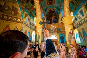 Elegant church ceremony with ornate Byzantine-style frescoes and golden decorations.