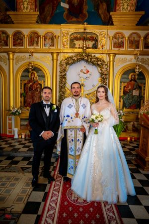 Formal wedding portraits in a Byzantine-style church with golden walls and religious artwork.