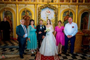 Wedding party gathering in an Orthodox church with colorful formal attire.