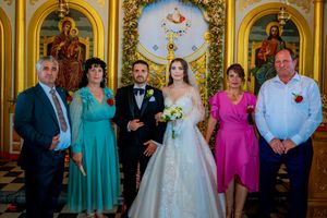 Wedding party poses in ornate Orthodox church with gilded iconostasis and checkered floor.