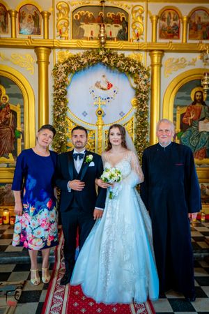 Formal wedding portraits taken inside Orthodox church with traditional iconostasis and religious artwork.