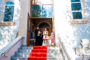 White church exterior with red carpet leading up concrete steps to entrance.