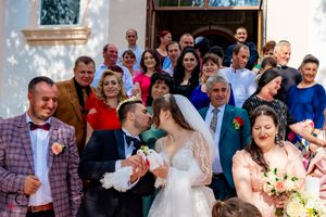 Large wedding group gathers for formal photos in front of a church exterior.