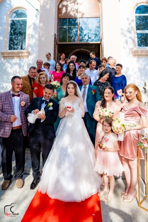 Festive wedding party poses for photos with bridesmaids in peach-colored dresses.
