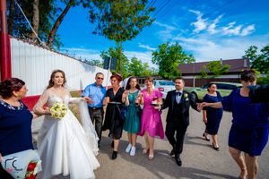Wedding party performs choreographed dance moves in an outdoor venue under blue skies.