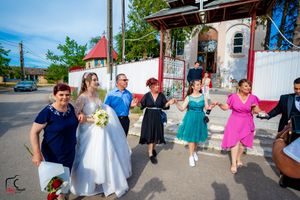 A joyful wedding celebration with dancers in colorful dresses outside a charming vintage chapel.