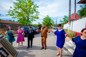 A lively wedding celebration with dancers in colorful attire outside a historic venue.