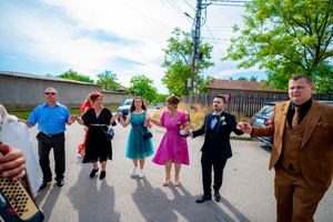Wedding celebration features a traditional dance line with accordion music on a sunny afternoon.