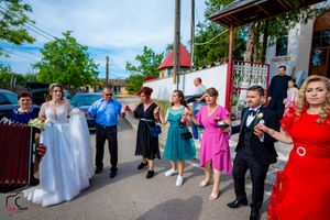 Joyful wedding party performs synchronized dance steps on sunny street.