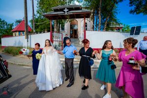 Wedding party celebrates outside a white gazebo with guests in colorful dresses during an outdoor celebration.