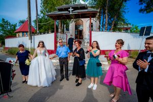 Wedding celebration outside a white gazebo with wedding party in colorful attire.