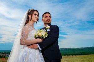 Wedding portrait in natural setting with dramatic blue sky and countryside views.