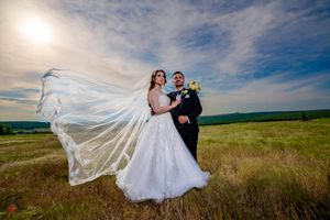 Wedding photography in golden sunlight across a vast meadow with white flowing dress.