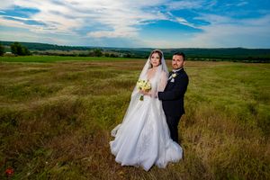 Elegant wedding photo shoot in a sweeping grassland landscape under blue skies.