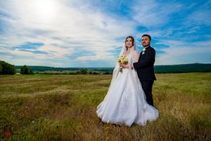 Romantic outdoor wedding portrait in a rustic field with mountains in the distance.
