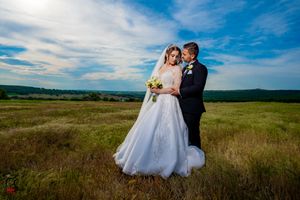 Wedding photography session in scenic countryside with dramatic sky and rolling hills.
