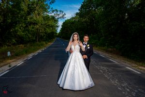 Wedding couple photographed on a tree-lined road creating a dramatic outdoor composition.