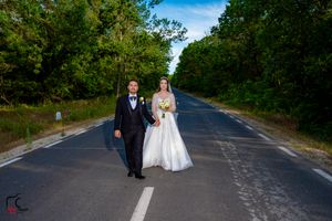 Elegant wedding photo taken on a secluded asphalt road with natural forest backdrop.