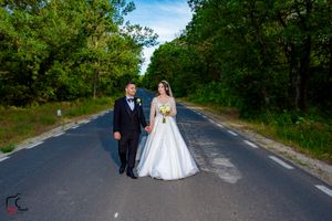 Newlyweds share a moment on a tree-lined asphalt road during their wedding photoshoot.