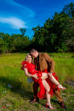 Couple shares a romantic dip pose in a wildflower meadow under blue skies.
