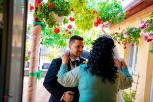 A covered patio decorated with hanging red flowers and greenery creates a romantic atmosphere.