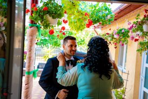 Guests gather under an outdoor covered walkway decorated with hanging floral arrangements.