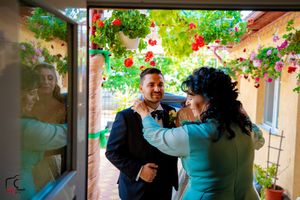 People celebrating at a wedding reception under a flower-covered patio with natural lighting.
